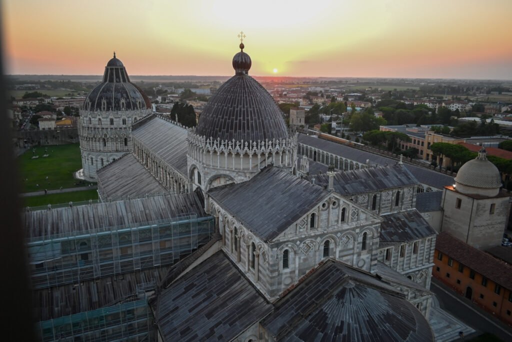 Alt: Blick auf die Kathedrale von Pisa bei Sonnenuntergang mit ikonischer Kuppel und mittelalterlicher Architektur, UNESCO-Weltkulturerbe, Italien.